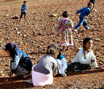 Niñas lanando y atrapando 5 piedras y niños corriendo alrededor. Pueblo Lahfart, Región Sidi Ifni, Marruecos, 2005